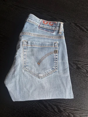 Dondup geroge - Snygga ljusblå jeans från George med klassisk femficksdesign och kontrastsömmar. Jeansen har en rak passform och är tillverkade i bomullsdenim. Perfekta för en avslappnad och trendig look.