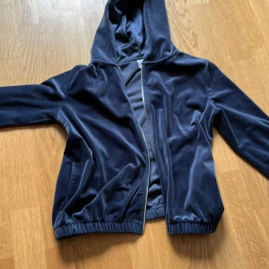 Mörkblå hoodie från Lindex - Säljer en snygg mörkblå hoodie från Lindex med texten 'Believe' i glittriga stenar på ryggen. Jackan har dragkedja och huva, perfekt för en cool och avslappnad stil. Den är i stl 146/152, men är lite liten för mig som brukar ha xs-s (170 cm lång) och är i väldigt bra skick! Hör av er om frågor!❤️(Säljer även på Vinted ifall man skulle vilja köpa där)