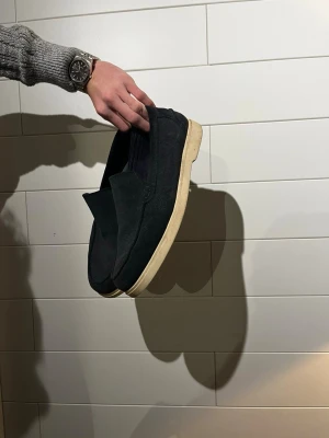 Zara loafers  - Säljer ett par svarta loafers med vit sula. Skorna har en stilren och enkel design i mockaliknande material och är lätta att ta på tack vare slip-on-modellen. Perfekta för dig som gillar en clean och avslappnad look.