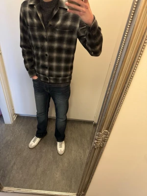 Rutig skjorta  - Stilren rutig skjorta från these glory days i svart och grått. Skjortan har klassisk krage, knäppning framtill och långa ärmar. Perfekt för dig som gillar en avslappnad men trendig look.