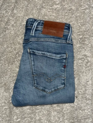 Replay Anbass jeans  - Ljusblåa Replay Anbass jeans med snygga slitningar, men en slim fit passform. Midja 36cm, längd 102cm. JAG SKICKAR EJ FLER BILDER NÄR JAG BÄR JEANSEN! för bättre inblick i passformen rekommenderar jag att googla på modellnamnet. För storleksguide kolla måtten noggrant då jeansen alltid kan vara uppsydda heller krympta och jag ej tar emot returer :) 1,69