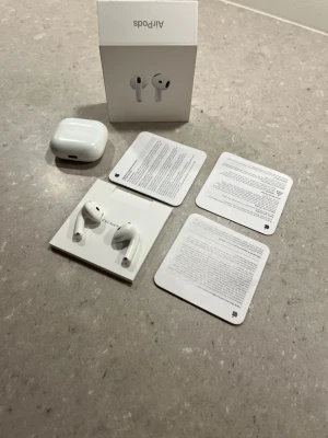 Apple AirPods 4  - Säljer ett par vita Apple AirPods 4 med tillhörande laddningsetui och originalförpackning. Trådlösa hörlurar med stilren design i blank vit färg, perfekt för musik, samtal och poddar. Köpta från Elgiganten. Obs utan noise cancellation!! Priset är ej hugget i sten.