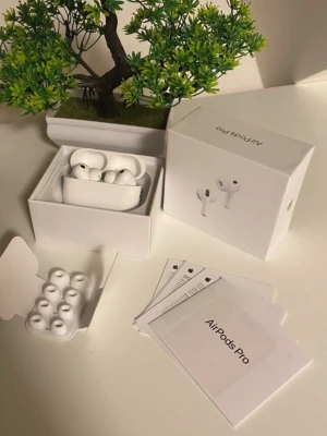 Apple AirPods Pro trådlösa hörlurar - Säljer ett par vita Apple AirPods Pro med laddningsetui och extra silikonpluppar. Hörlurarna är in-ear och har en stilren, kompakt design i plast. Perfekt för dig som vill ha grymt ljud och smidig anslutning till din iPhone eller andra Apple-enheter.