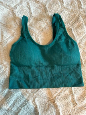 Turkos sport-bh med breda axelband - Säljer en turkos sport-bh med breda axelband och ribbad struktur. Bh:n har en längre modell som ger extra stöd och komfort. Tillverkad i stretchigt material som formar sig efter kroppen. Perfekt för träning eller en aktiv vardag.