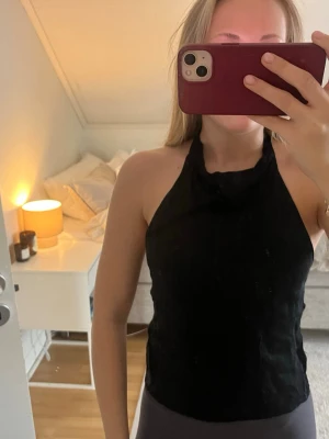 Svart halterneck topp - Säljer en svart halterneck topp med ärmlös design och hög hals. Inga defekter! 