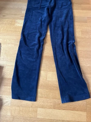 Mörkblåa mjukisbyxor med fickor - Mörkblåa mjukisbyxor i mjukt velourmaterial från Juicy Couture. Nypris omkring 900-1 200, men säljer för 350 och sänker pris vid snabb affär. Har knappt använts och fortfarande mjuka i materialet. Skriv vid fler bilder. Klicka ej på köp nu!