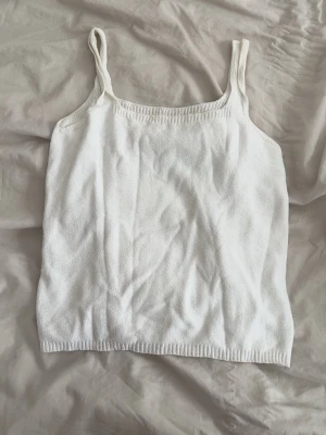 Vit stickad linnetopp - Säljer en enkel och stilren vit stickad linnetopp med smala axelband. 