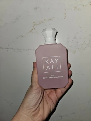 Kayali Yum Boujee Marshmallow 81 parfym 100ml - Kayali Yum Boujee Marshmallow 81 100ml är en parfym i en matt, ljusrosa flaska med vit, multifasetterad kork. Doften har noter av fresia, jordgubb, rosa marshmallow, krämig kokos, vispad vanilj och rosa mysk. Flaskan har en modern, kantig design och känns lyxig och trendig. Helt ny 
