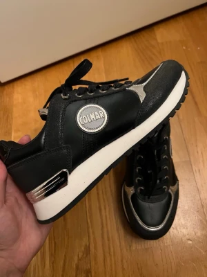 Sneakers Colmar  - Svara skor (sneakers) från Colmar med läder/silvriga detaljer. Lite platå i sulan. Helt nya. Nypris 1600kr. 