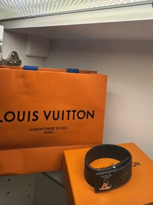 Louis Vuitton armband - Snyggt svart armband från Louis Vuitton med klassiskt LV-spänne i silverfärg. Skärpet har diskret monogrammönster och är tillverkat i exklusivt skinn. Perfekt accessoar för att lyfta din outfit. Passar till tjej och kille 
