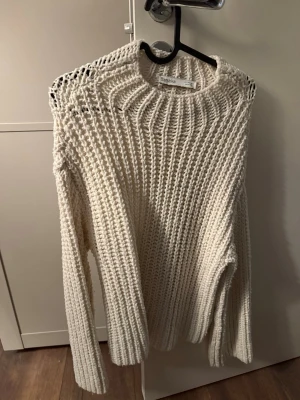 Vit grovstickad tröja från Bershka - Säljer en vit grovstickad tröja från Bershka med rund halsringning och långa vida ärmar. Tröjan har ett luftigt, chunky stickat mönster som ger en oversize avslappnad och trendig look. Perfekt att styla med jeans eller kjol.