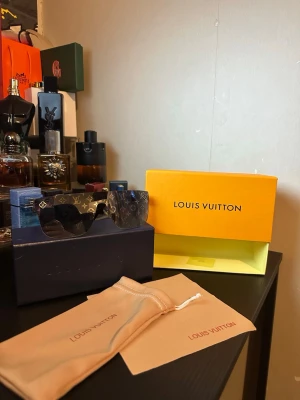 Louis Vuitton monogram solglasögon - Snygga solglasögon från Louis Vuitton med ikoniskt monogrammönster på glasen. Modellen har en bred, rektangulär form och mörka linser. Kommer med originalförpackning och tygpåse med Louis Vuitton-logga.