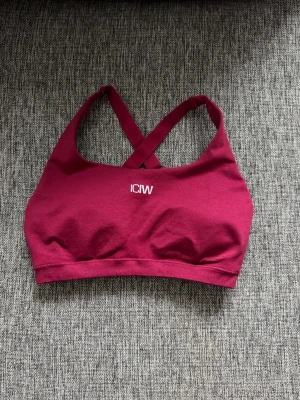 Smooth sport-bh från ICANIWILL - Snygg vinröd sport-bh från ICANIWILL med korsade axelband i ryggen och justerbara band. Tillverkad i mjukt och stretchigt material som ger bra stöd vid träning. Liten vit logga framtill. Perfekt för gymmet eller andra sportaktiviteter.