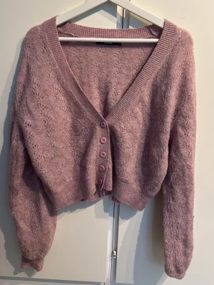 Ljuslila stickad kofta med knappar - Mysig ljuslila stickad kofta med v-ringning och fem matchande knappar framtill. I storlek XS men funkar perfekt som en S i storlek!