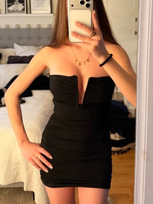 Svart mini klänning - Snygg svart mini klänning med djup v-ringning framtill. Prislapp kvar. 