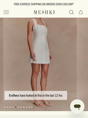 Vit kort klänning från Meshki - Stilren vit kort klänning från Meshki med halterneck och bred knytning i nacken. Helt oanvänd med prislapp kvar.