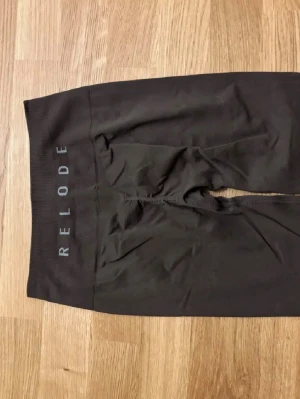 Svarta seamless leggings från Relode - Säljer ett par svarta seamless leggings från Relode med hög midja och bred resår. Materialet är stretchigt och följsamt, perfekt för träning eller chill. Diskret logga på linningen. Snygg passform som framhäver benen.