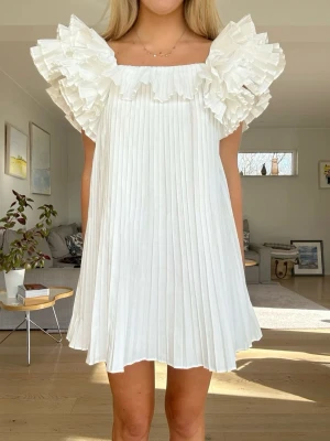 Vit plisserad klänning med volangärm - Supersöt vit klänning med plisserat kjol och volangärmar. Perfekt för studenten eller sommaren. Klänningen är i nyskick. Kan tänka mig sälja för lägre vid snabbt köp. Säljer även samma klänning i storlek XS, bara att gå in på min profil💕💕