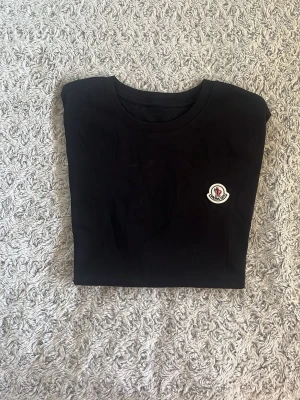 Moncler T-shirt - Svart långärmad tröja från Moncler med rund halsringning och den klassiska Moncler-loggan broderad på bröstet. Enkel och stilren design som passar perfekt till jeans eller kjol.