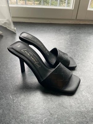 Svarta flätade pumps från New Look - Säljer ett par svarta pumps från New Look med flätad rem över foten och öppen häl. I storlek 36, knappt använda!☺️