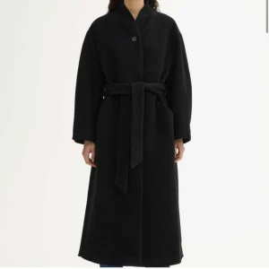 Oversized kappa från House of Dagmar - Elegant svart ullkappa med dubbelknäppning, klassisk krage och avtagbart bälte. Modellen heter Oversize Belted Coat och är i storlek 34 men är oversize och kan passa upp till 38.  I jättefint skick. Nypris 6500. 
