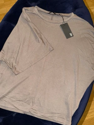 Beige t-shirt från 157 - En basic beige t-shirt från 157 med rund hals och korta ärmar. Tillverkad i mjukt material som känns skönt mot huden. Perfekt att matcha med jeans eller shorts för en clean och enkel look.