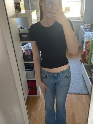 Svart ribbad topp från Lindex - En svart ribbad topp från Lindex med rund halsringning. Toppen har en croppad passform och är tillverkad i mjuk bomullsmix som känns skön mot huden. Perfekt att styla med jeans eller kjol. Den är för liten för mig så därför säljer jag den.