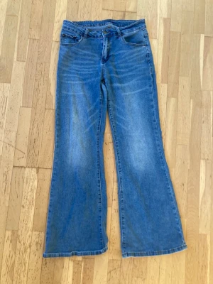 Blå flard jeans med klassisk look - Säljer ett par blå jeans med rak passform och klassisk femficksdesign. Jeansen har normal midja och är tillverkade i slitstarkt denimtyg. Perfekta för dig som gillar enkel och tidlös stil. Dragkedja och knapp framtill.