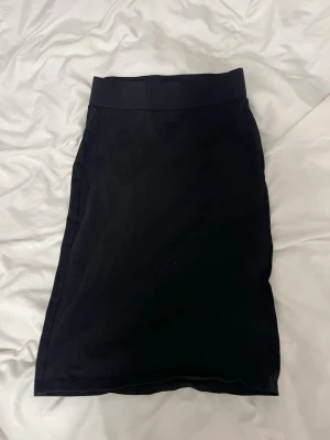 Svart långkjol med hög midja - En stilren svart långkjol med hög midja och rak passform. Kjolen är enkel och klassisk, perfekt att matcha med olika toppar. Tillverkad i ett mjukt material som ger en bekväm känsla.