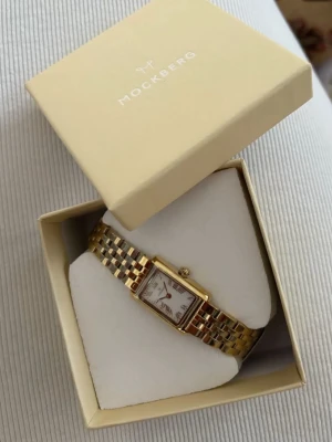 Mockberg guld klocka rektangulär - Säljer min klocka från mockberg, bara ett år gammal. Jätte fin och knappt använd 🫶🏻🫶🏻