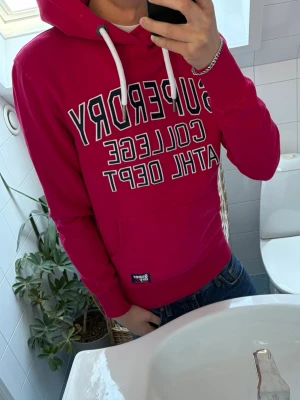 Superdry hoodie - Tja! Säljer en sjukt fet röd Superdry Hoodie. Otroligt skönt material och bra passform. 10/10 skick, som ny. Modellen är ~180 Cm. Hör av dig vid minsta fundering!