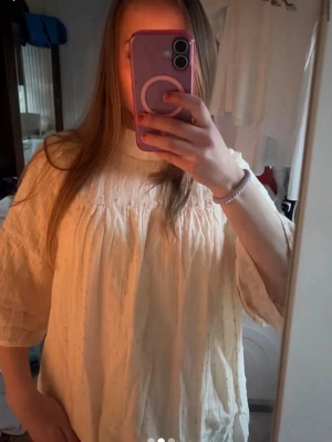 Ljusgul vid blus med trekvartsärm - Säljer en ljusgul, luftig blus med trekvartsärmar och hög hals. Blusen har ett avslappnat, oversized snitt och fina veckdetaljer framtill. Tillverkad i ett mjukt, strukturerat tyg som ger en skön känsla. Perfekt att styla med jeans eller kjol.