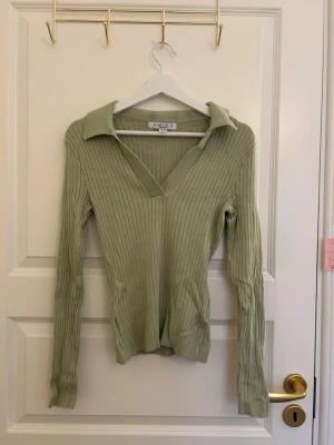 Ljusgrön ribbstickad tröja Amisu - Trendig ljusgrön ribbstickad tröja från Amisu med djup v-ringning och krage. Långärmad modell i mjukt material som sitter figurnära. Perfekt för lager-på-lager och snygg till både jeans och kjol.