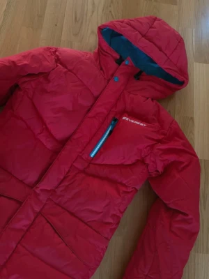 Röd dunjacka Everest - Märke• Everest                                             Storlek•38                                                          Köpt för• ca 1000kr                                      Mitt pris• 200kr                                     Beskrivning• huva och dragkedja framtill. Jackan har en bröstficka med blå dragkedja och två stora fickor på sidorna. Perfekt för vintern eller höst. Materialet är dun