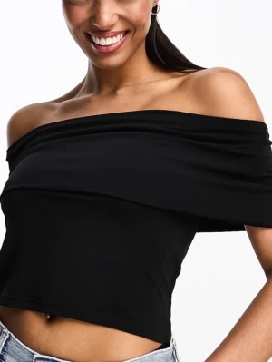 Svart offshoulder croppad topp - Säljer en svart offshoulder topp med croppad passform. Toppen är ärmlös och har en bred kant som sitter snyggt över axlarna. Perfekt att styla med jeans eller kjol för en trendig look. Perfekt för sommaren, men även på vintern