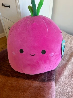 Squishmallow - En rosa squishmallow som ser ut som en lök. Den är rolig och mjuk.