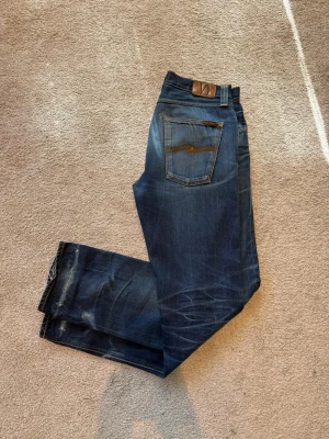 Dry Nudie Jeans - Tja, jag säljer ett par dry jeans från Nudie jeans med snygga whisckers och honeycomb fades. Storlekslappen är avklippt men skulle uppskatta storleken till 32/34, be om mått för att vara på den säkra sidan! Det är en gammal nudie modell som inte säljs längre vilket gör de rare och unika!       MVH Freddysgarderob