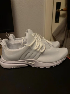 Nike vita Presto sneakers - Säljer ett par helvita Nike Presto sneakers med klassisk låg siluett. Skorna har ventilerande mesh-ovandel, elastiska snören och en mjuk, stötdämpande sula. Perfekta för dig som gillar stilrena och sportiga sneakers med modern design. Passar inte mig så säljer dom. 