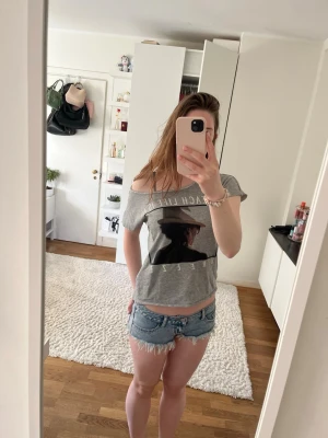 Blå jeansshorts med fransar - Säljer ett par ljusblå jeansshorts med råa, fransiga kanter och klassisk femficksdesign. Shortsen har låg midja och är tillverkade i denim med slitna detaljer för en avslappnad look. Perfekta för varma sommardagar.