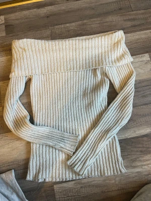 Off shoulder stickad tröja Lindex - Säljer en beige/off white  ribbstickad off shoulder-tröja från Lindex. Tröjan har långa ärmar och bred krage som kan bäras nedanför axlarna. Materialet är mjukt och stretchigt, perfekt för en trendig och avslappnad look. Nästan aldrig använd och passar även S och M. Kontakta mig vid frågor. Nypris 400kr