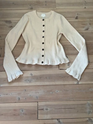 Krämvit ribbad tröja med volang - Säljder denna söta stickade tröjan med volang från H&M💕Har nästan aldrig använt så den är i mycket bra skick. Storlek S.