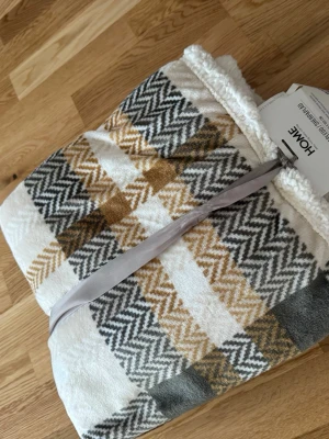 Mjuk sherpapläd med rutmönster - Säljer en supermjuk och varm sherpapläd från HOME i storlek 130x160 cm. Pläden har ett snyggt rutmönster i vitt, grått och senapsgult med fluffig sherpa på baksidan. Perfekt att mysa med i soffan eller som extra lager i sängen.