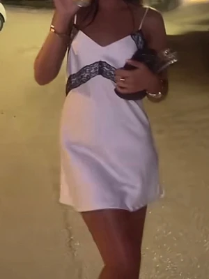 Vit klänning med spetsdetaljer - Så otroligt snygg satin klänning med svarta spetsdetaljer!! Helt ny med prislapp kvar, nypris 599. Säljer direkt för 499kr!! Storlek s 😍😍💞