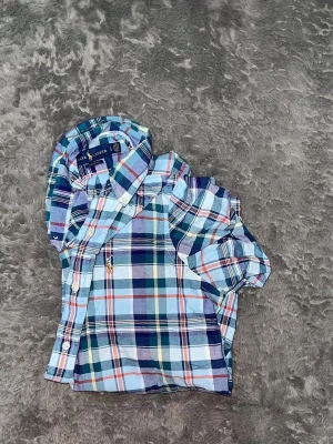 Polo Ralph Lauren Classic Fit Plaid Shirt - snygg rutig skjorta från Polo Ralph Lauren i modellen Classic Fit, vilket ger en avslappnad och bekväm passform. Skjortan har den ikoniska broderade loggan på bröstet och button-down krage.  • Skick: Mycket fint skick 