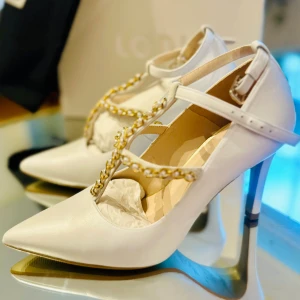 LODI vita klackskor strl 37 – NYA – brudskor / festskor i läde - Säljer ett par exklusiva vita klackskor från spanska kvalitetsmärket LODI, modell Rimola-Pi (Galaxia Avorio C1).  ✨ Helt nya – endast provade i butik, aldrig använda ✨ Levereras med originalkartong, dustbag (skopåse) och allt emballage kvar ✨ Perfekta som brudskor, till student eller andra festliga tillfällen  Detaljer: • Äkta läder av hög kvalitet • Spetsig tå • Elegant kedjedetalj med pärlor • Tillverkade i Spanien • Storlek 37  Nypris ca 1900 kr.  💰 Pris: 1750 kr Inköpta i Spanien. Slutsålda