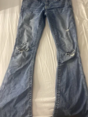 Bootcut jeans med slitningar och paljetter - Ljusblå lågmidjade bootcut jeans ifrån Gina 14+