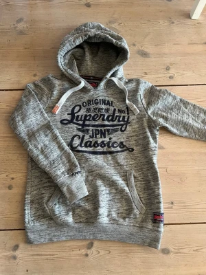 Superdry Hoodie - Nu säljer jag en riktigt snygg hoodie från Superdry i storlek M. Tröjan är i väldigt bra skick och har en normal passform. Lite vintage stil vilken är ganska trendigt just nu, perfekt till våren!! Skriv vid funderingar!☀️🙌