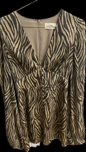  Adoore Florence dress   - Cool zebramönstrad klänning från Adoore med v-ringning och knappar framtill. Klänningen har långärmade puffärmar och markerad midja som ger en snygg siluett. Materialet är lätt och har en lyxig känsla. Använd endast en gång några timmar. Tvättad en gång, nyskick. Säljes pga byte till annan storlek. Fast pris. (Kostar 1495 kr ny plus frakt på hemsidan)
