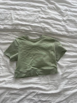 Ljusgrön ribbad croppad träningstop - Trendig ljusgrön croppad träningstopp med korta ärmar och rund hals. 
