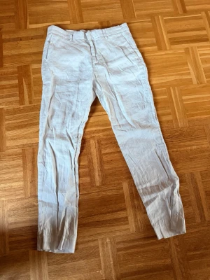 Vita linnebyxor från H&M Slim Fit - Snygga vita linnebyxor från H&M i modellen Slim Fit. Byxorna har klassisk rak passform med bälteshällor och är tillverkade i ett lätt och luftigt linnetyg, perfekt för varma dagar. Enkla att matcha med olika stilar och accessoarer.
